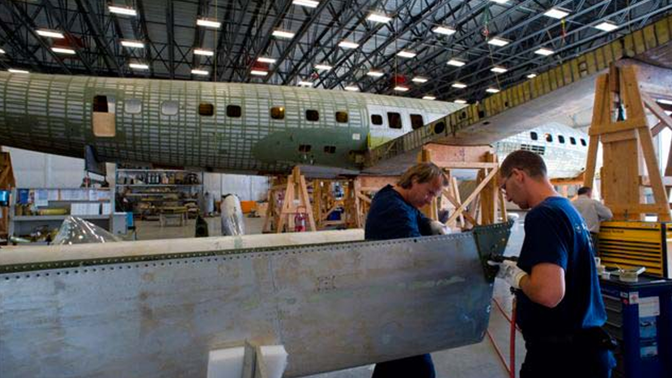 Workers cutting steel pieces for airplane resoration project.