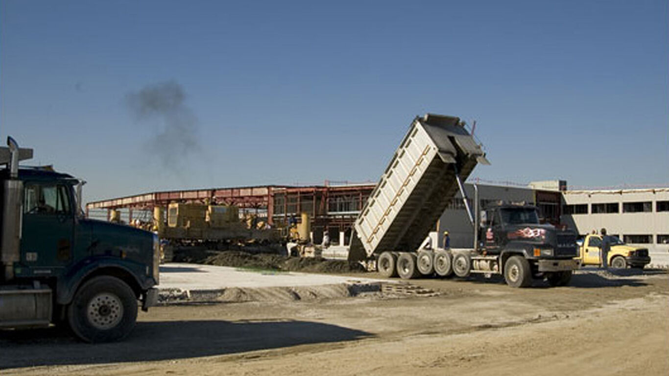 A dump truck pouring dirt out for a warehouse